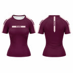 Front and back views of a women's short-sleeve athletic jersey in deep burgundy with light pink sleeve panels and trim, featuring the name 'RAINE' printed on the chest and along the sleeves, and a vertical 'RAINE' mark on the back.