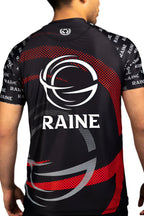 Back of a man wearing a black and red short-sleeved BJJ rash guard with the brand logo 'RAINE' featured on the back